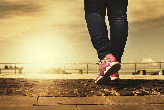 Active woman walking in sneakers at sunrise, highlighting exercise’s benefits for healthy, glowing skin